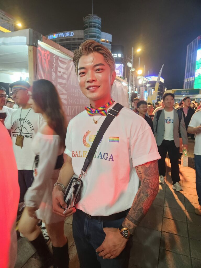 A smiling person stands on a Taipei street at night