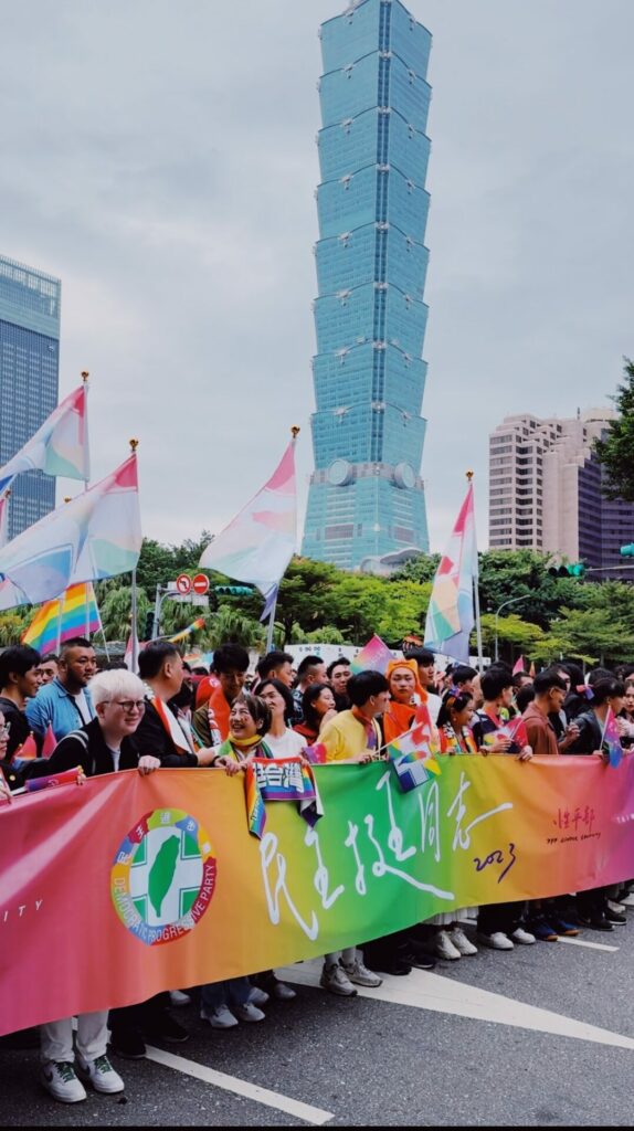 People march in the Taiwan Pride 2023 parade with the Taipei 101 Tower in the background