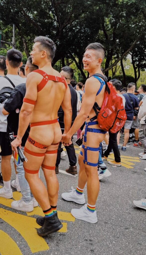 Two men in fetish gear with their backsides exposed hold hands in the Taiwan Pride parade