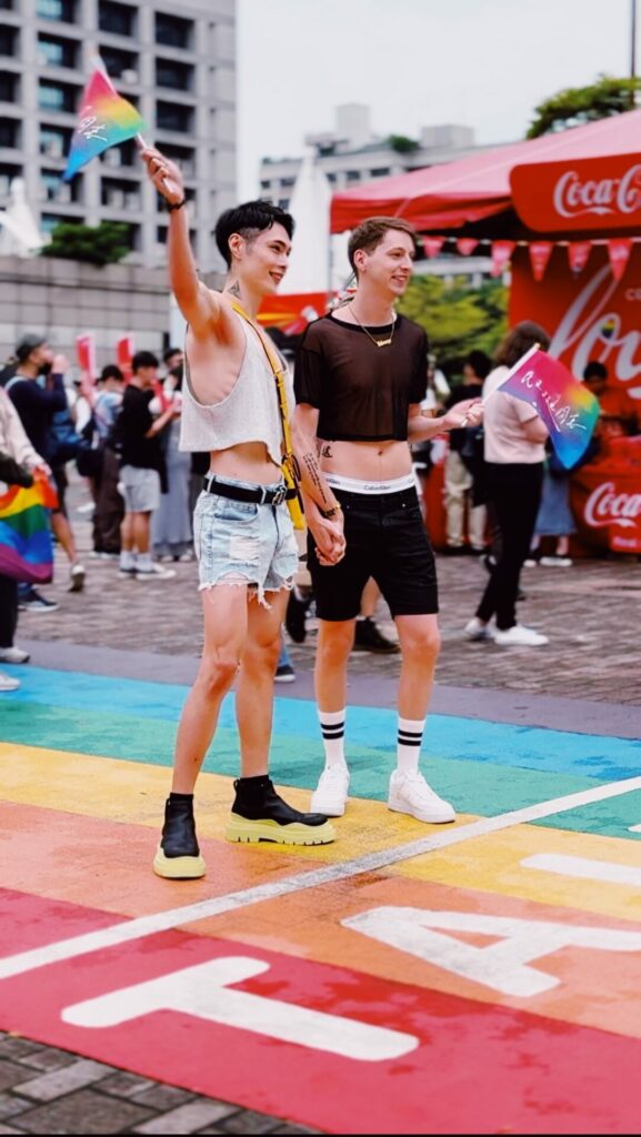 Two people holding hands over a rainbow street crossing during  theTaiwan Pride 2023 parade