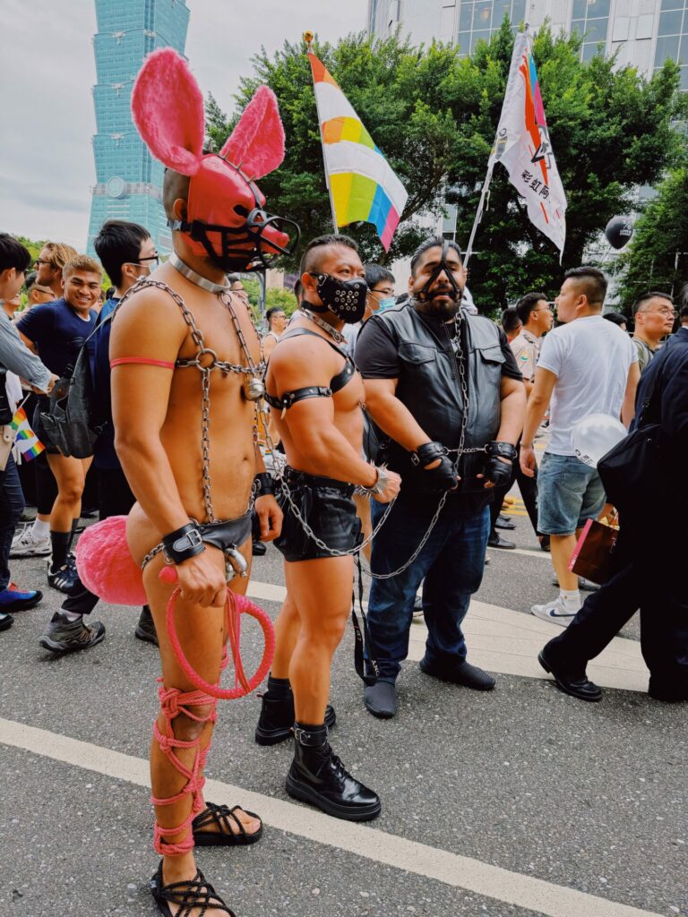 A group of men wearing fetish gear at the Taiwan Pride 2023 parade with Taipei 101 in the background