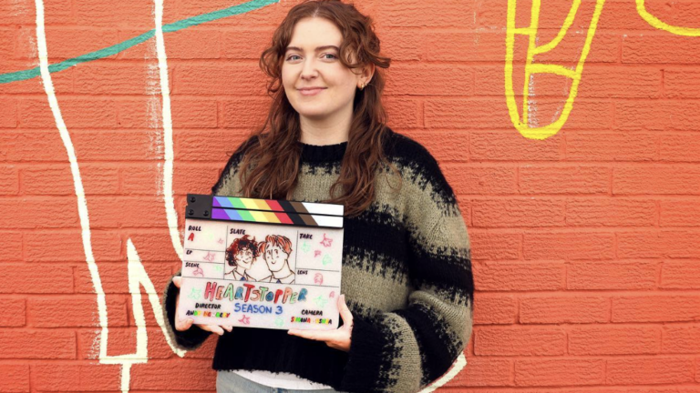 Alice Oseman holds up a clapper board ahead of season 3 of Heartstopper