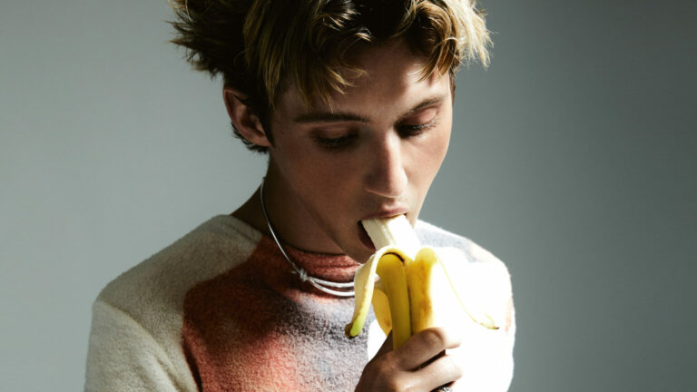 Troye Sivan bites on a banana