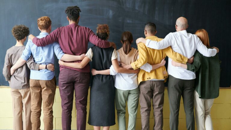 A group of people standing with their backs to the camera in front of a chalk board