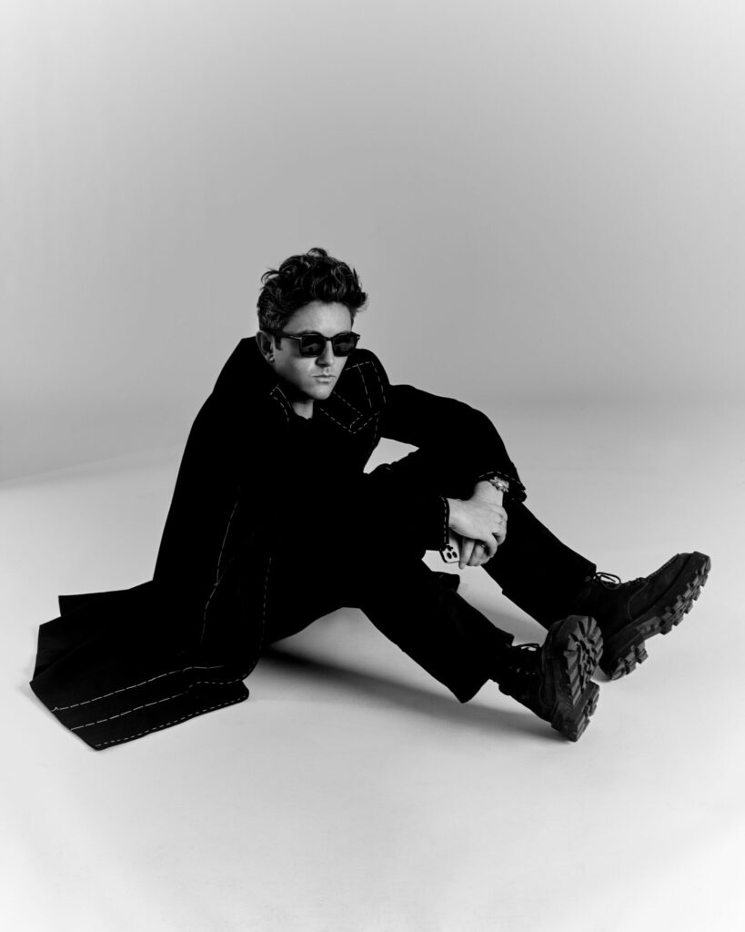 Black and white image of Daniel Fletcher sitting on the floor in a studio