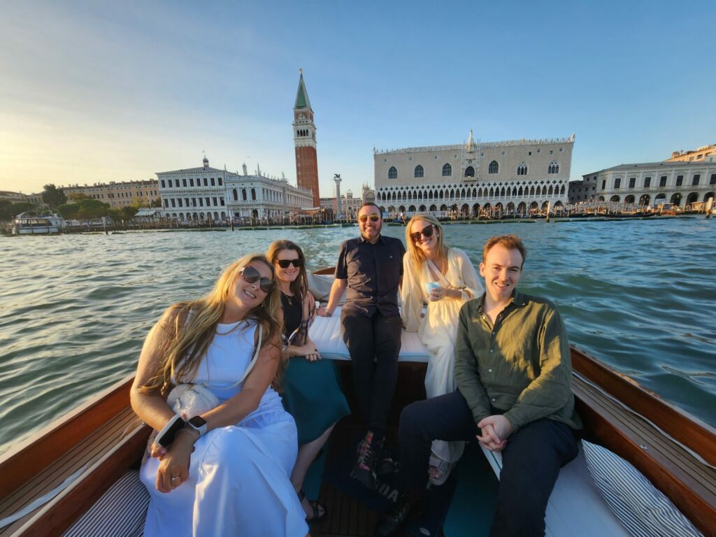 A group of people sit on a speedboat in Venice