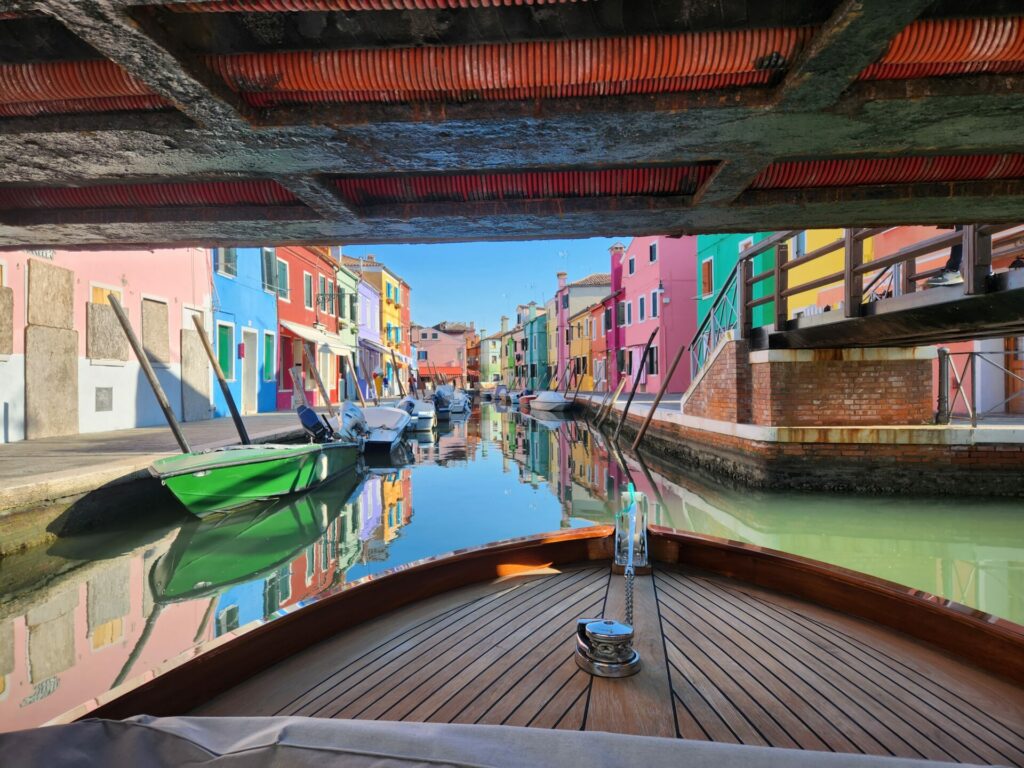 Shot of colourful buildings in Venice from a boat as it goes under a bridge