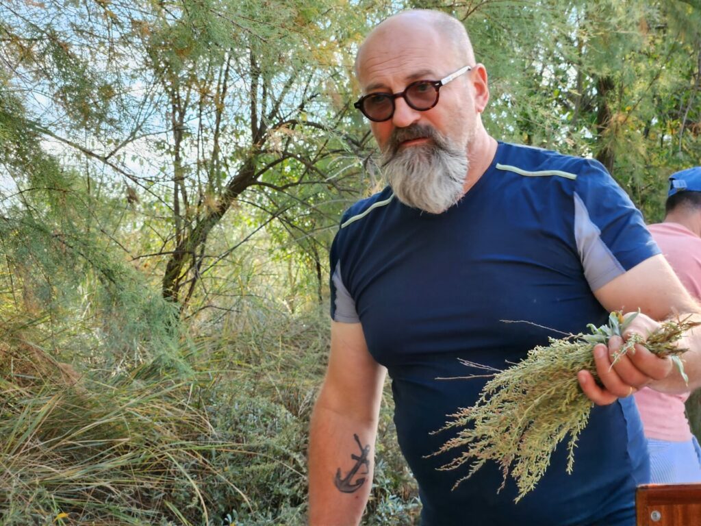 A man with a blue T-shirt holds some herbs 
