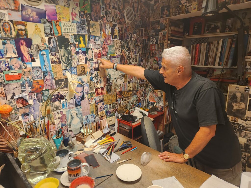 A man points at a wall of artworks