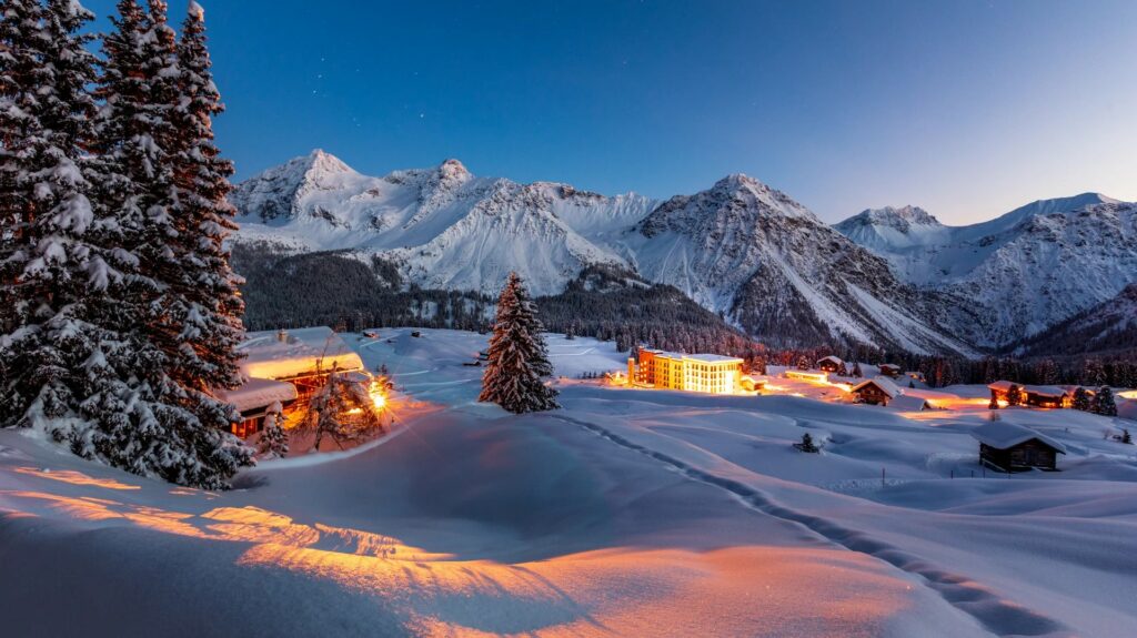Wide view of Arosa with snowy mountains behind wooden buildings
