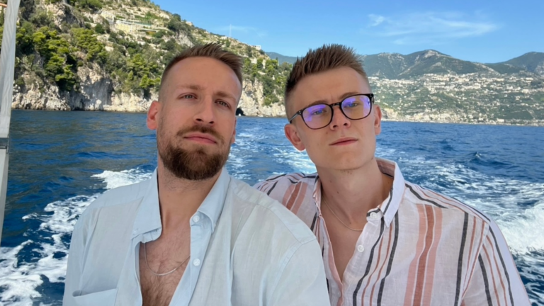 Two men standing next to each other with rushing water behind them and a mountain backdrop