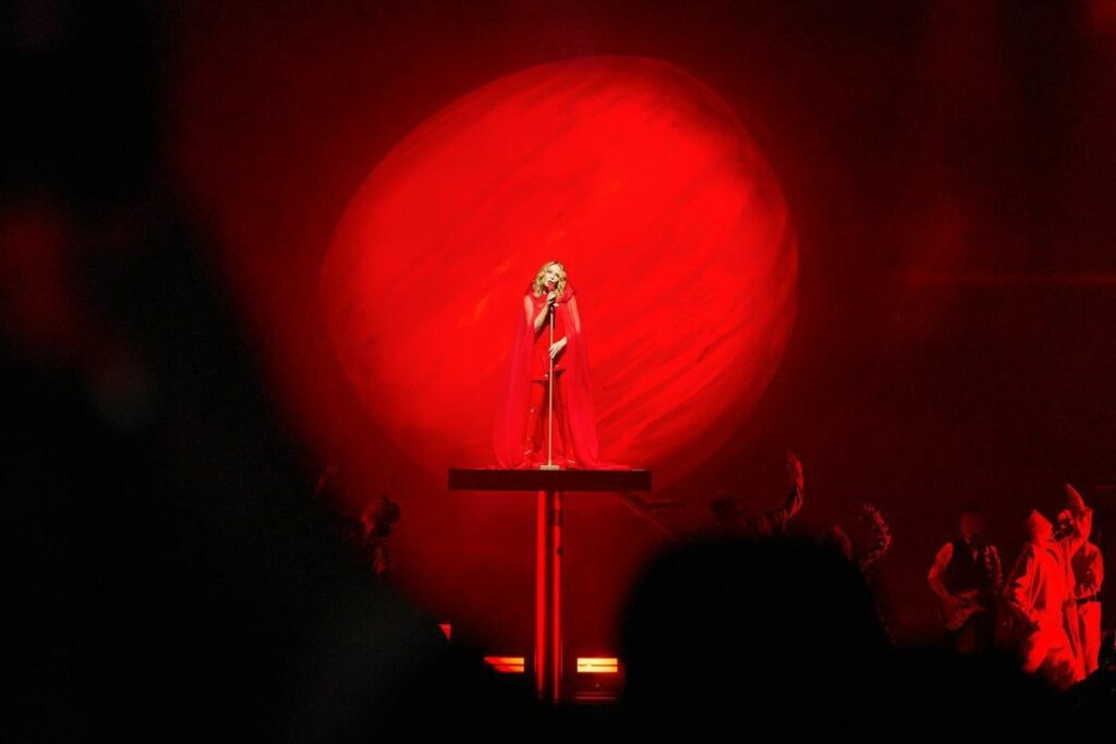 Kylie performs during her Las Vegas residency standing on a tall red podium wearing a red outfit