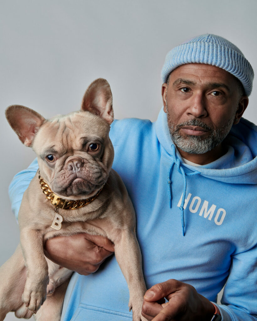 A man wearing blue poses with a dog