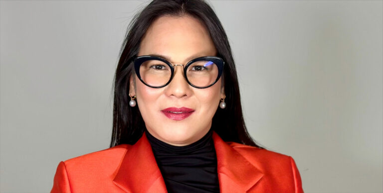 Profile shot of a woman in a red jacket with black hair and black glasses