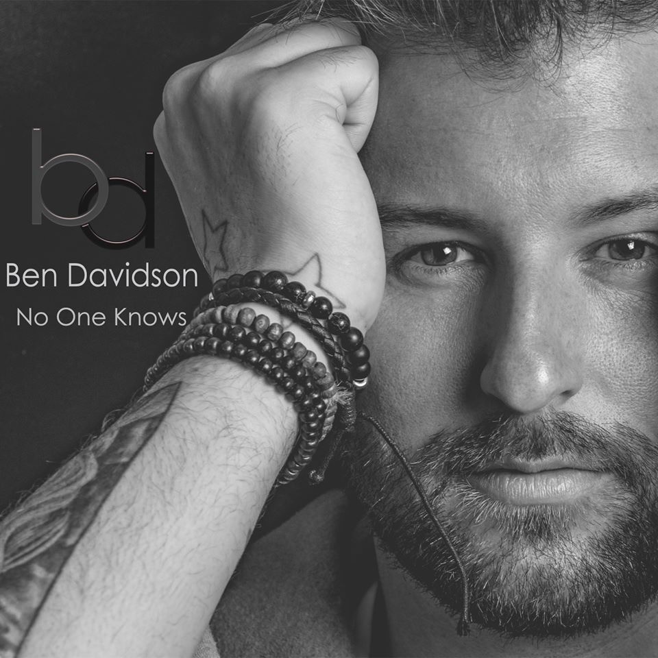 A black and white album cover shot featuring a man with a beard resting his face on his hand