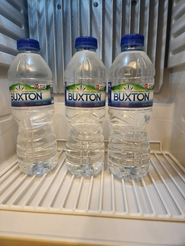 A fridge with Buxton mineral water bottles inside
