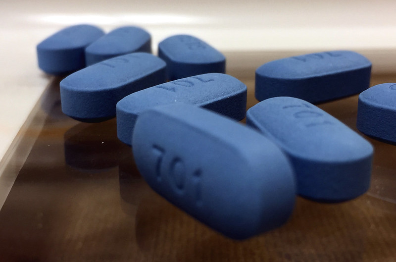Stock photo of several blue pills with the number 701 on them sitting on a brown table