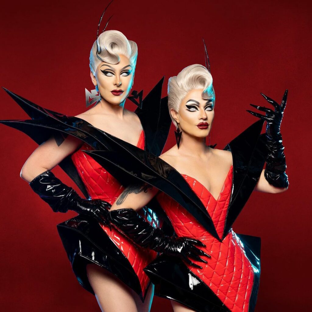 Promo shot of The Boulet Brothers against a red background. They are wearing red and black latex