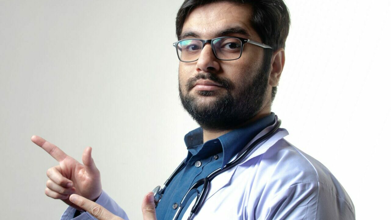 Stock image of a male doctor pointing sideways with neutral expressions