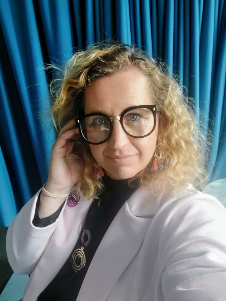 Portrait shot of a person with blond curly hair and glasses