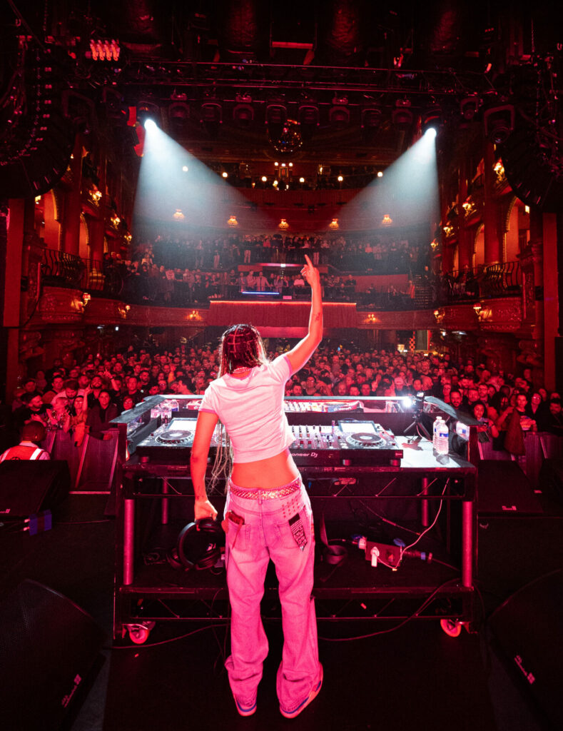 Rear shot of Phoenix Brown playing a DJ set in front of a crowd of people at KOKO Camden