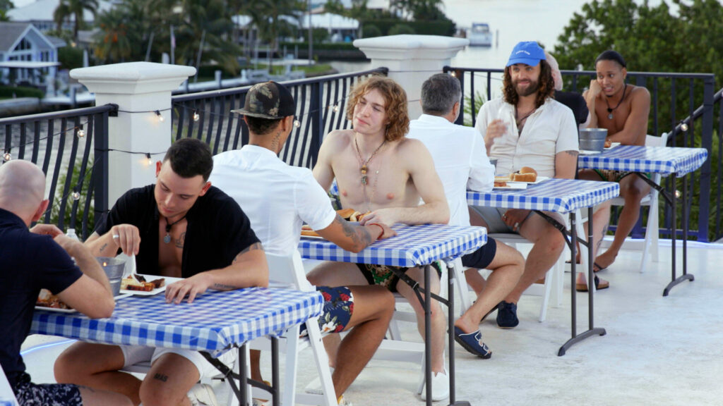 Still from For the Love of DILFS showing a group of men speed dating at tables