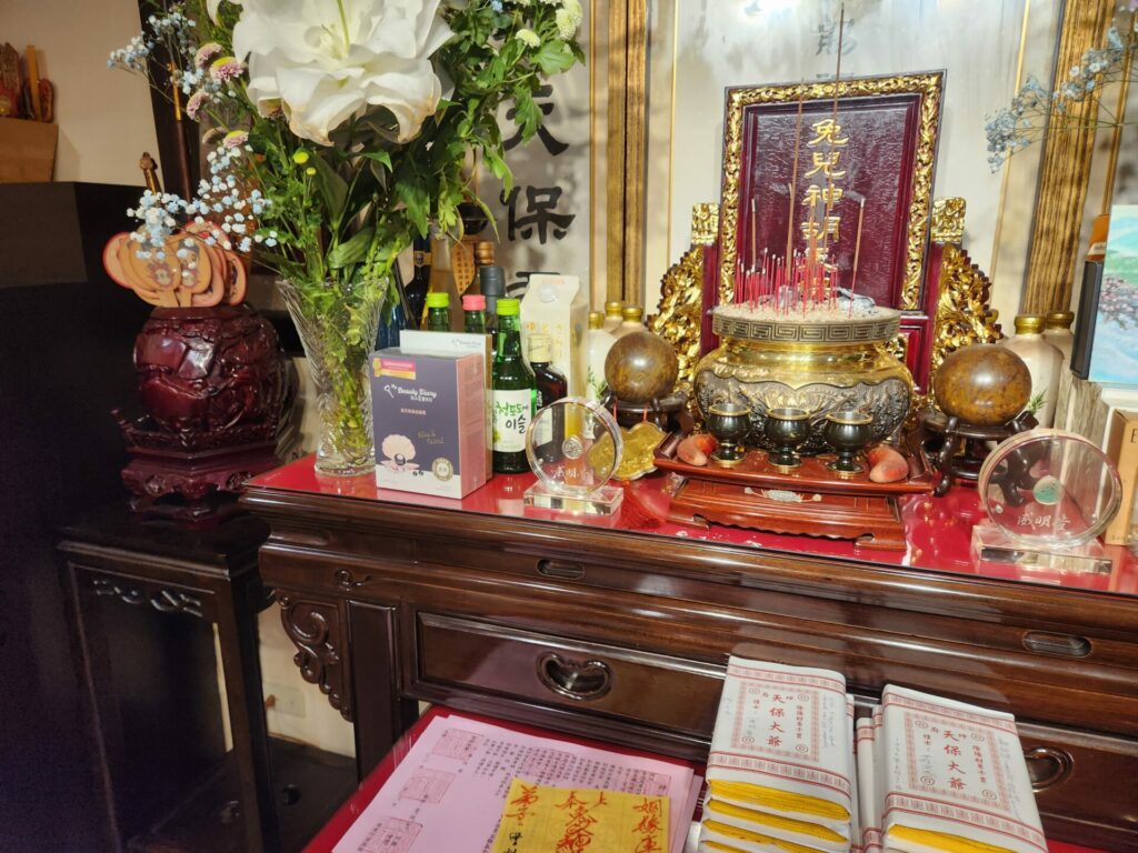 Close up of a shrine covered in incense and paper money offerings