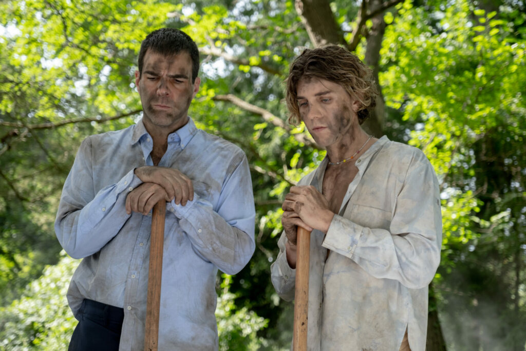 Still from Down Low showing Zachary Quinto and Lukas Gage covered in mud holding shovels
