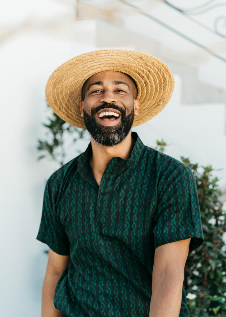 A smiling man wearing a green shirt and straw hat