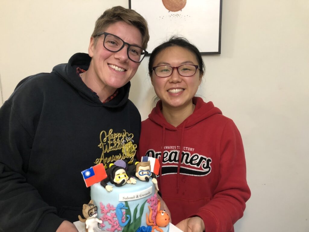 Two smiling women hold a wedding anniversary cake