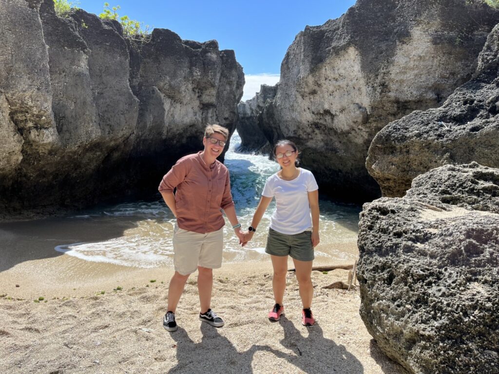 Two women stand in a beach alcove holding hands