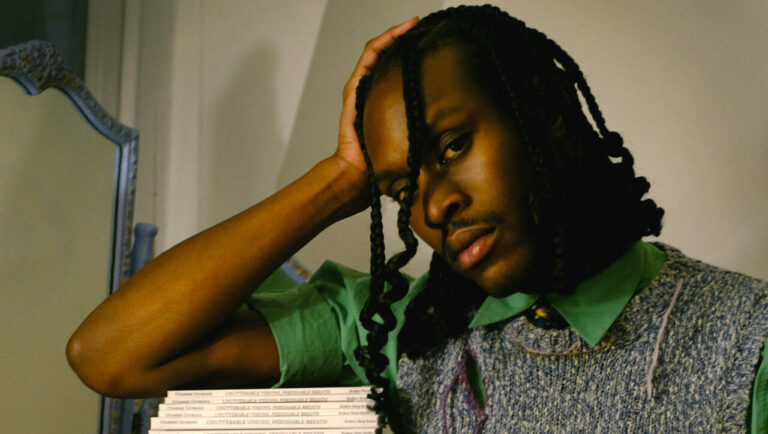 Otamere Guobadia rests his arm on a pile of books