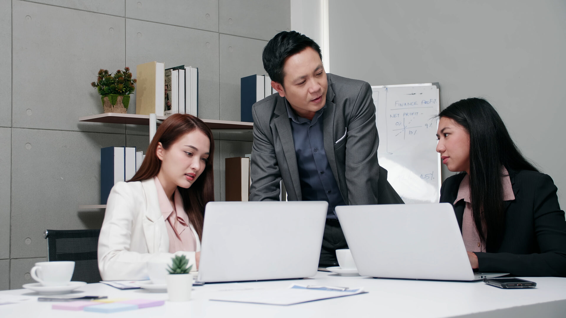 Stock image of three people in office working around a desk