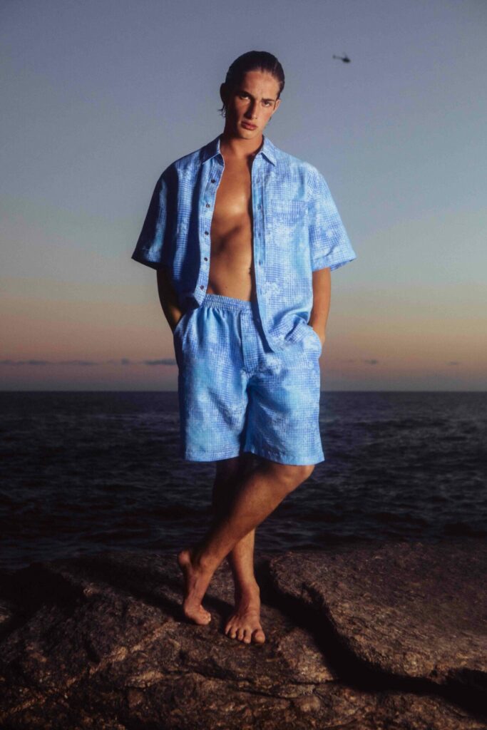 A man poses in swimwear on a beach