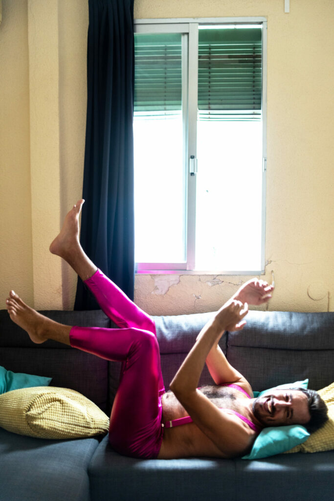 Luis Maura in pink lycra trousers lying on a sofa (Image: Elska)
