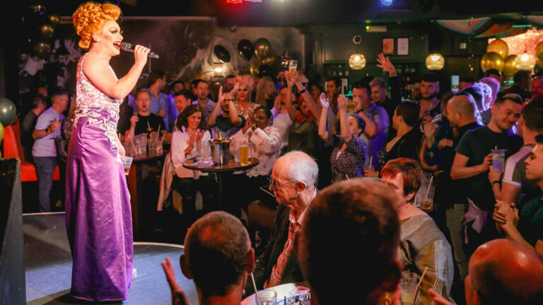A drag queen performs to a packed nightclub