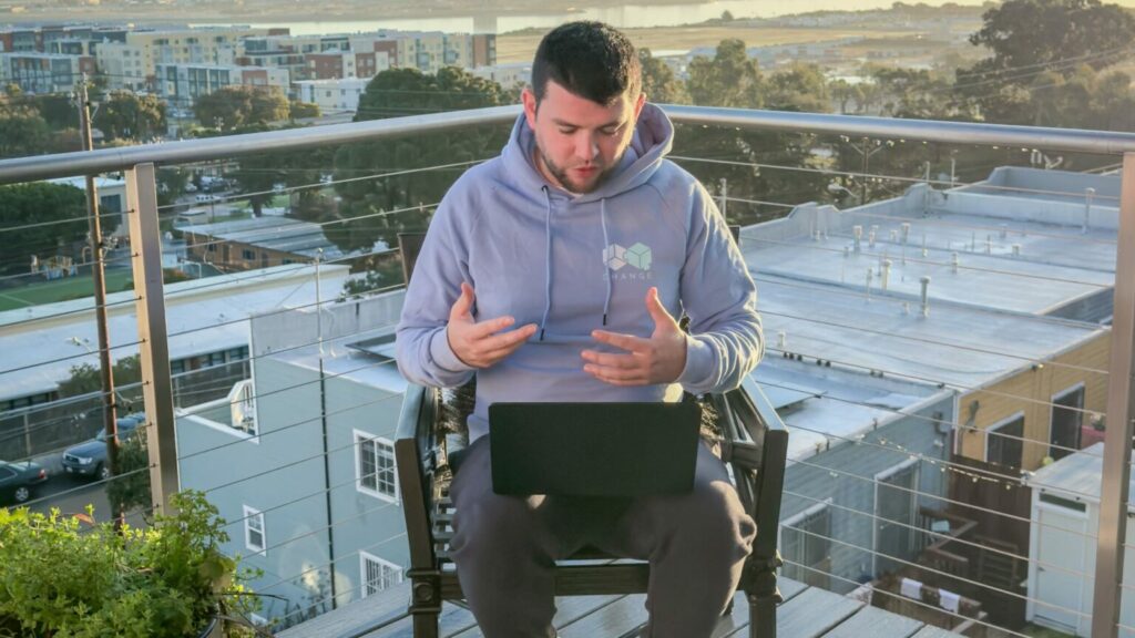 A man sitting on a chair with a laptop on his lap