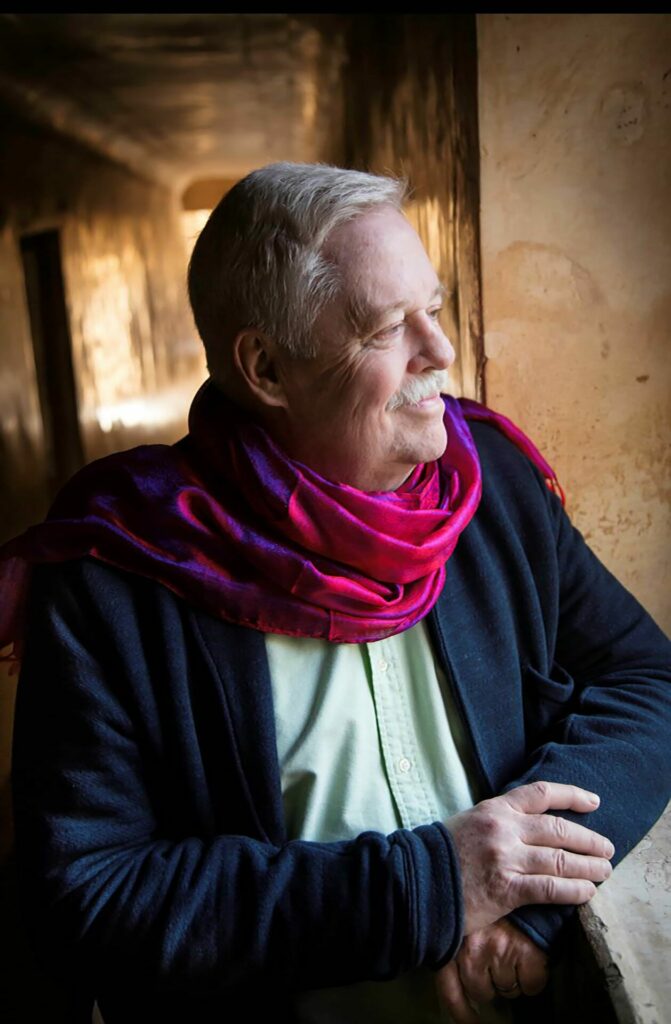 Armistead Maupin wearing a red scarf and blue blazer