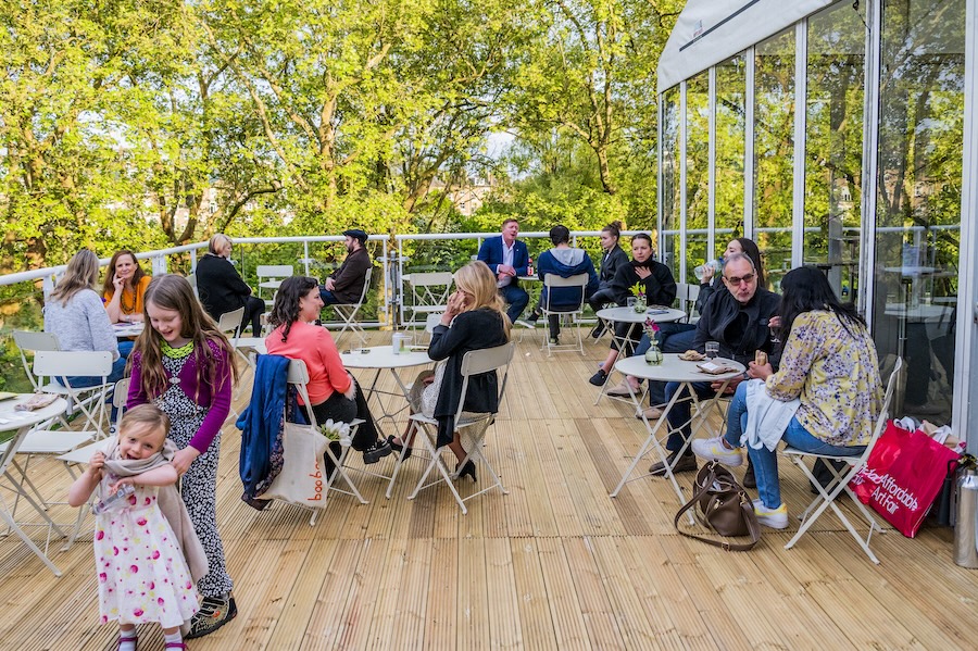 People sit at tables and chat on a rooftop terrace