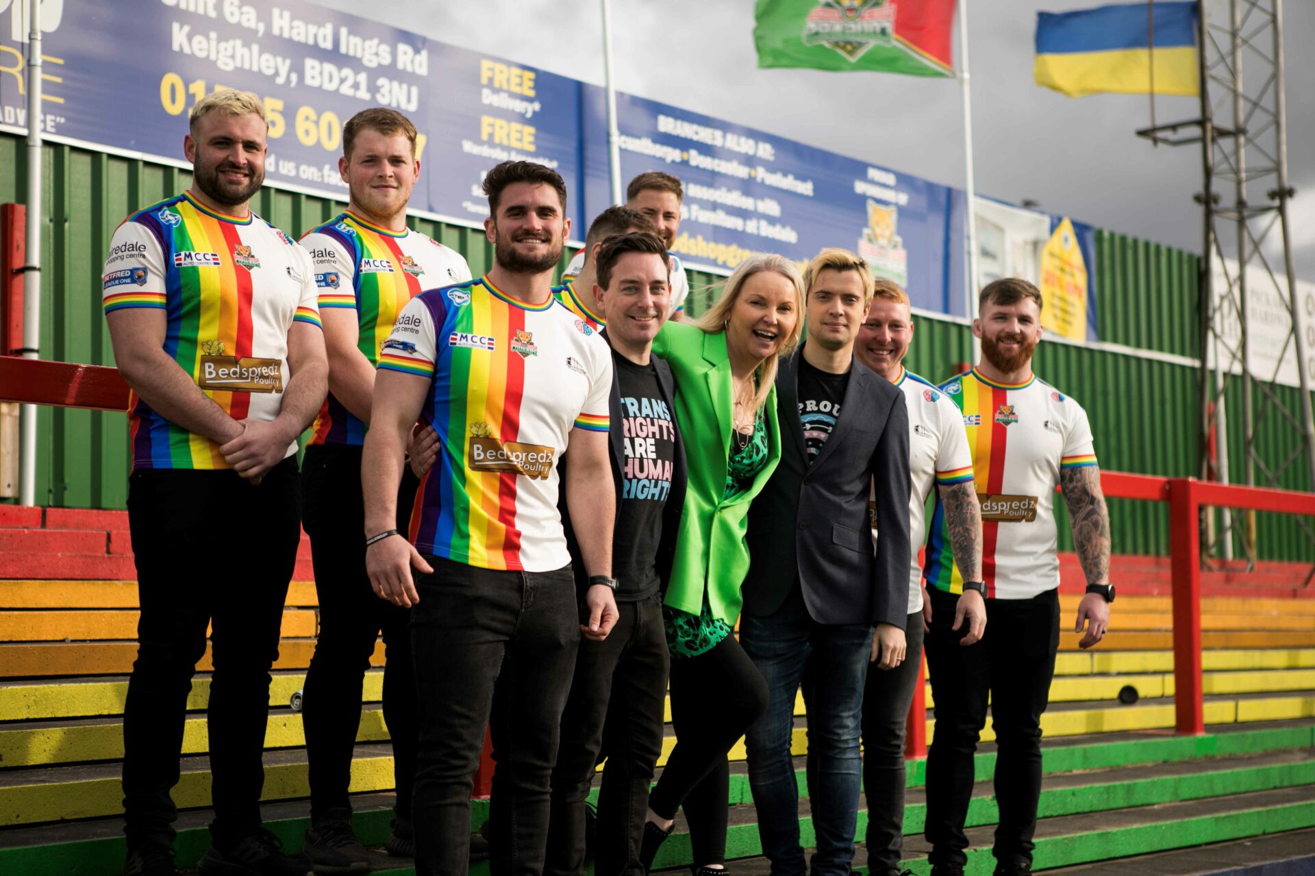 India Willoughy stands next to rugby players on a green rugby pitch