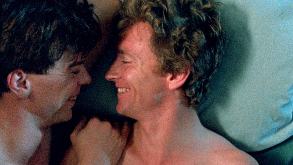 two men in bed laughing together