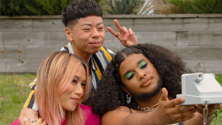 Three friends of varying gender identities relax in a park