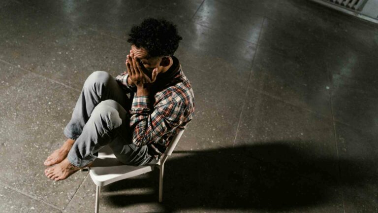 A man sits on a chair looking stressed