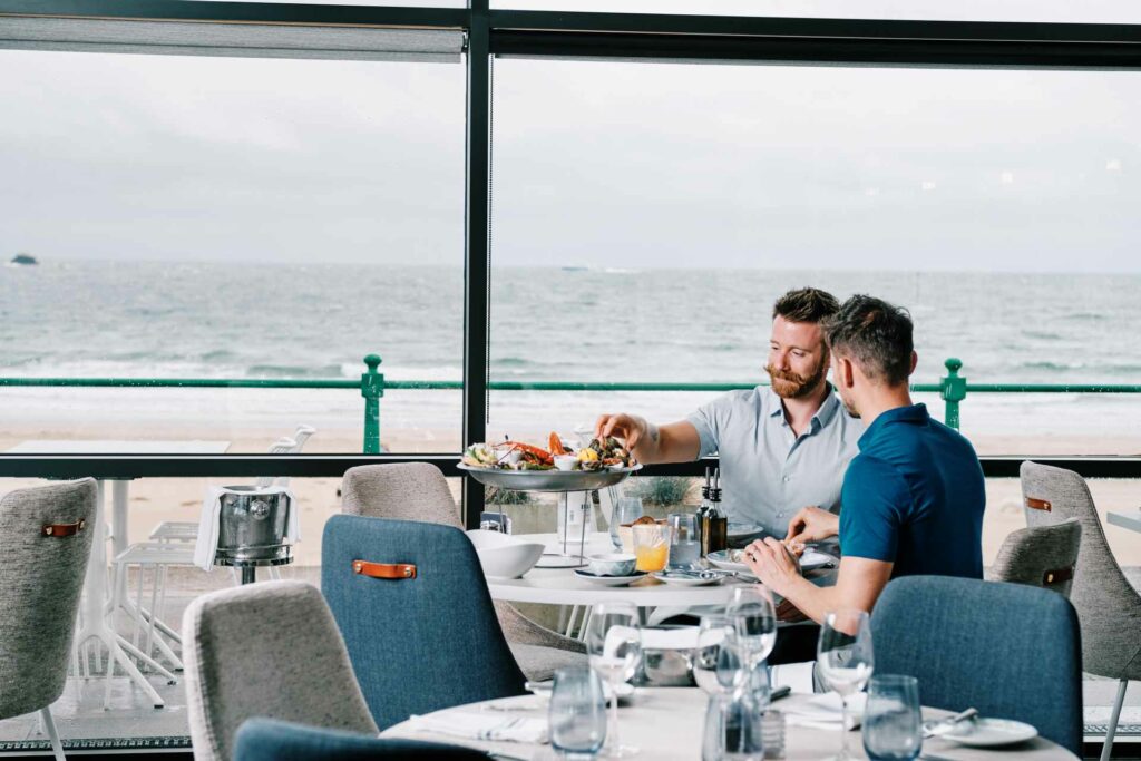 Two man eating in a restaurant overlooking the ocean