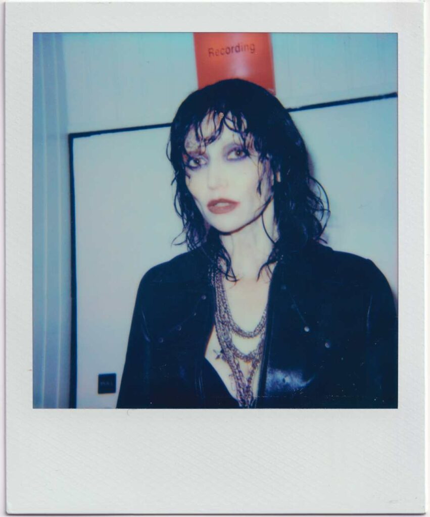 A Polaroid-style photo of a person in a black outfit and red lipstick.