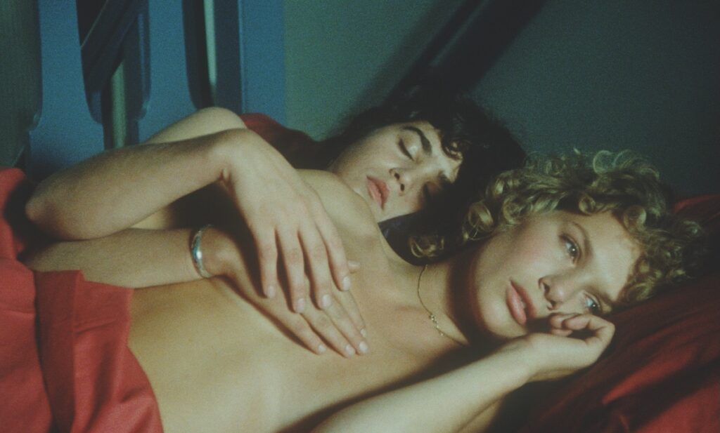 two women lying in a bed topless
