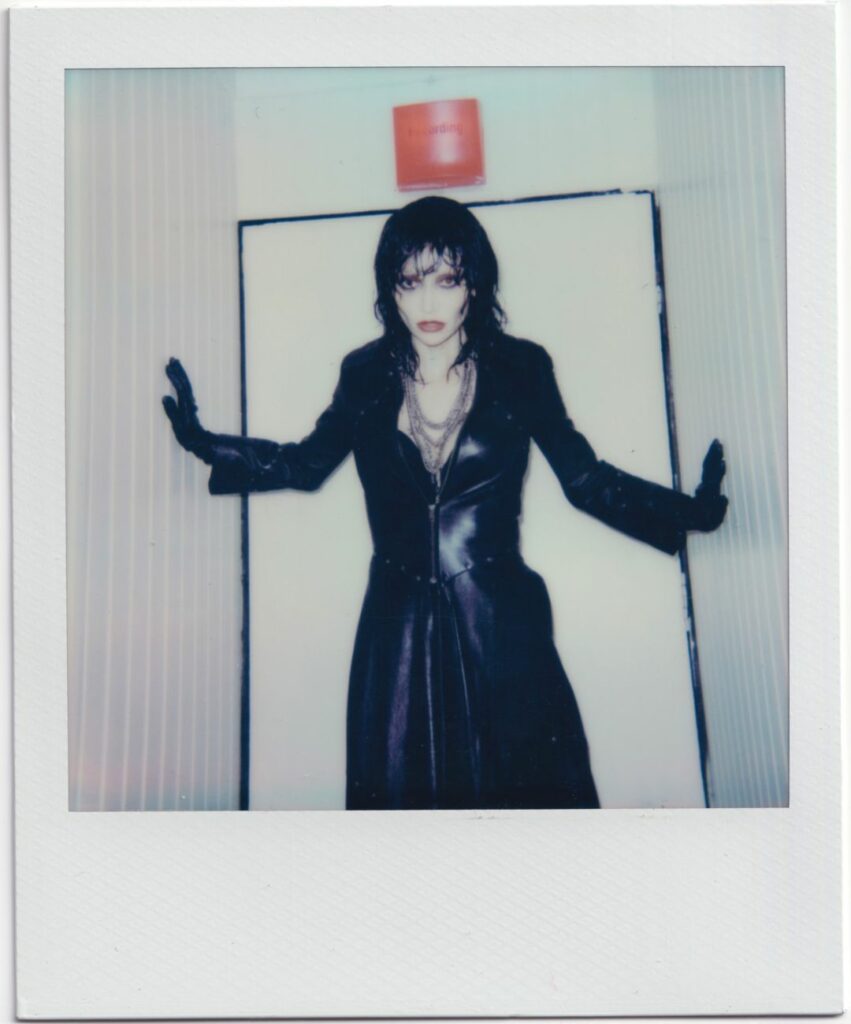 A Polaroid-style photo of a person in a black outfit and red lipstick.
