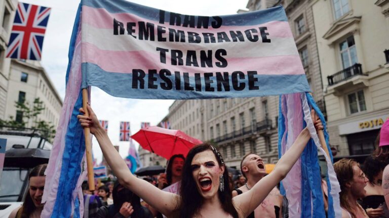 A group of people at a march holding a banner that reads "Trans remembrance, trans resilience."