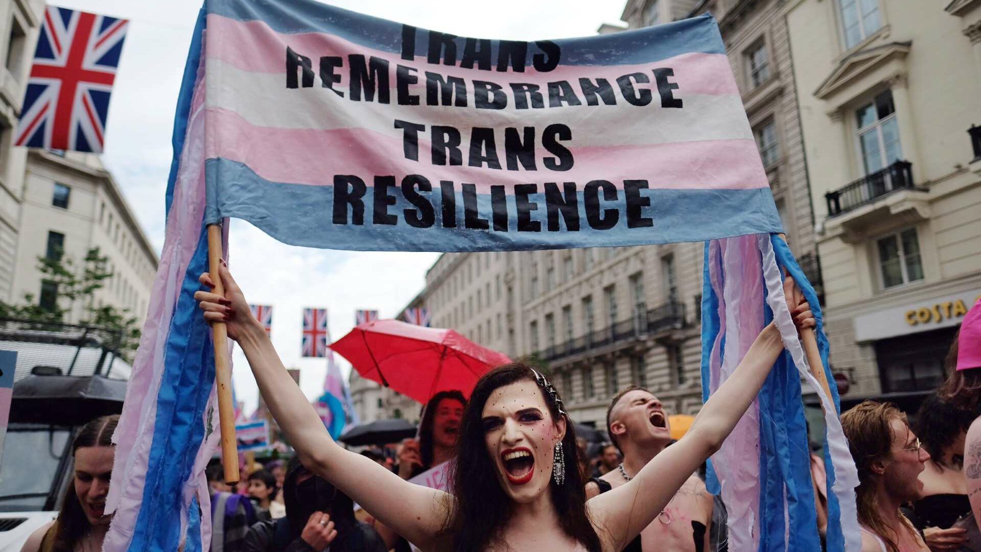 A group of people at a march holding a banner that reads "Trans remembrance, trans resilience."