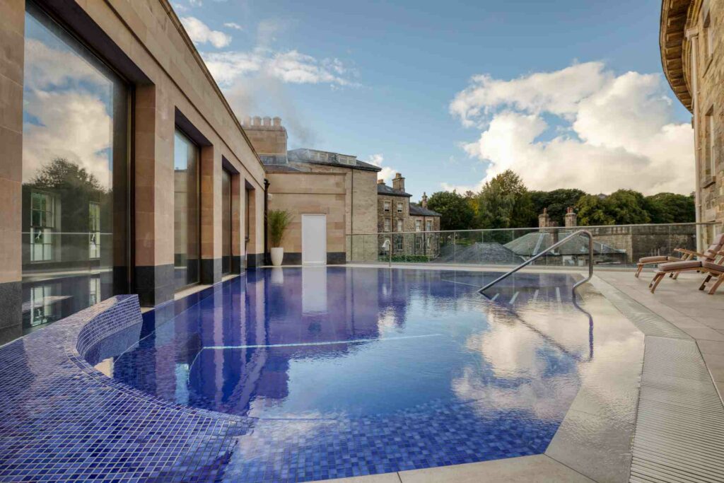 Outdoor thermal pool at Buxton Crescent Hotel, reflecting the blue sky and clouds